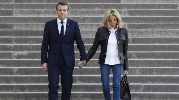 French President Emmanuel Macron, left, with his wife Brigitte Macron arrive to attend an interview with BFM television.