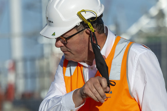 Premier Daniel Andrews removes his mask on Tuesday.