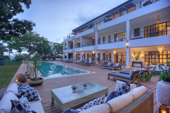 A central dining and lounge area wraps around a chequerboard-bottomed pool.