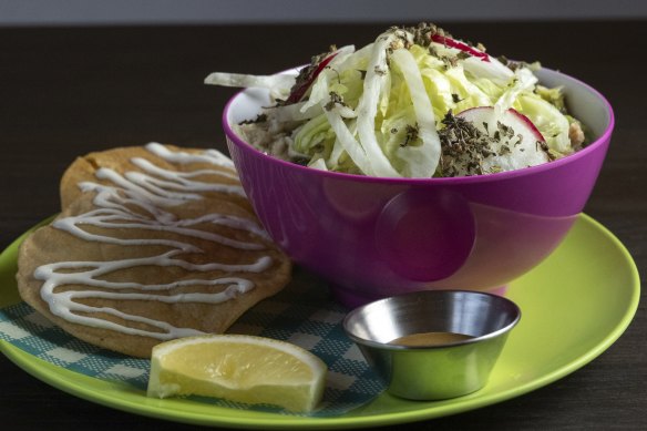 Pozole, a light broth topped with shredded lettuce and radish, can be seasoned to taste.