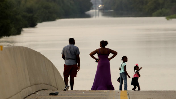 A family surveys floodwaters in Houston in the aftermath of Hurricane Harvey in September 2017, in Houston. 