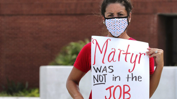 Rachel Bardes holds a sign in front of the Orange County Public Schools headquarters as teachers protest with a car parade around the administration centre in Orlando, Florida.