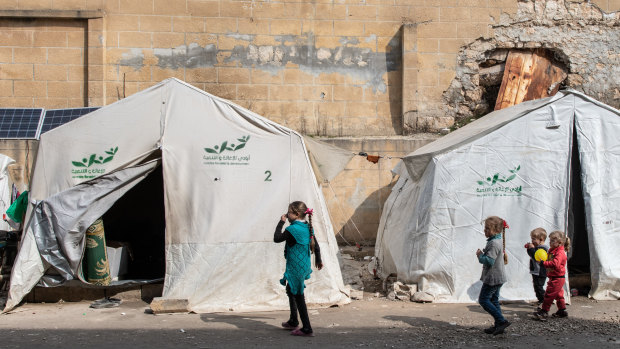 Displaced Syrian children walk past their tents in a stadium turned into a makeshift refugee shelter in Idlib on Thursday.