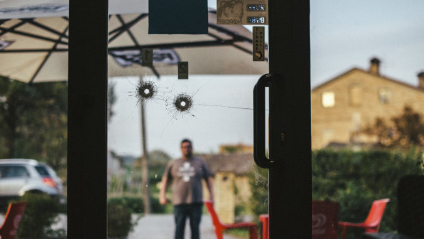 Bullet holes on the door of the H7 pub, where the gunman had worked until he was fired in October, in Macerata.