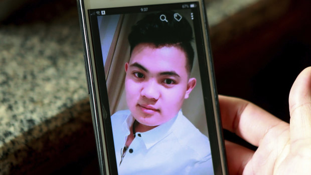 Hoang Thi Ai, mother of Hoang Van Tiep, who is feared to be among the England truck dead, hold a phone showing a photo of him in Dien Thinh village.