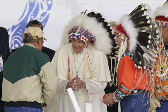 Pope Francis dons a headdress during a visit with Indigenous peoples at Maskwaci.