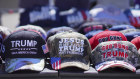 Hats reading, “God, Guns and Trump” and “Jesus is my saviour, Trump is my president” are sold at a campaign rally.