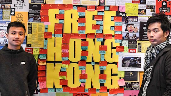 Dennis Chui, left, and Silver Lee stand with the Lennon Wall they helped construct at the University of Technology, Sydney.