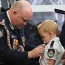 RFS Commissioner Shane Fitzsimmons pins the posthumous service medal of Geoffrey Keaton onto his son, Harvey. Geoffrey died fighting bushfires in December.