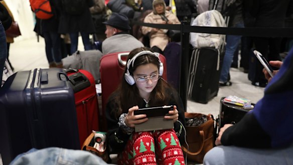 Passengers at Gatwick airport settle down to wait for their flights following the delays and cancellations brought on by drone sightings near the airfield, in London.
