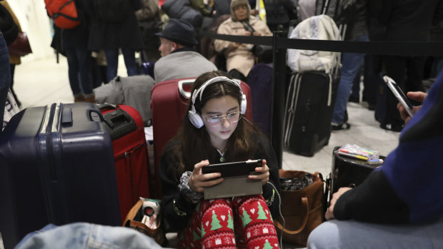 Passengers at Gatwick airport settle down to wait for their flights following the delays and cancellations brought on by drone sightings near the airfield, in London.