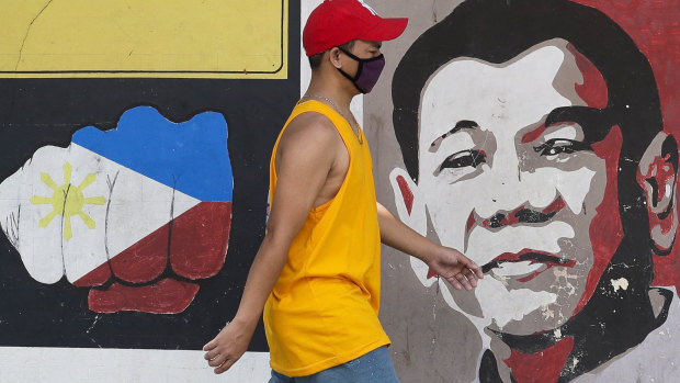 A man wearing a protective mask walks past an image of Philippine President Rodrigo Duterte in Manila.