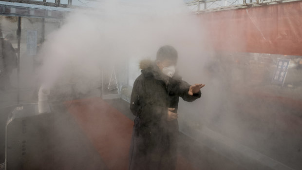 A man walks through a disinfectant spray in order to return home at a residential complex in northern China's Tianjin.