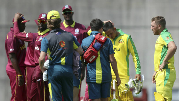 Players gather around Usman Khawaja (second right) after he was struck on the helmet.