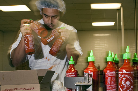 A packer grabs bottles of sriracha for packing at a Huy Fong facility.