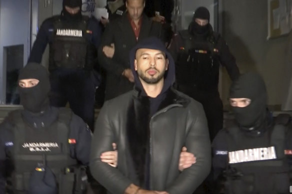 Andrew Tate is led away by police in the Ilfov area, north of Bucharest.