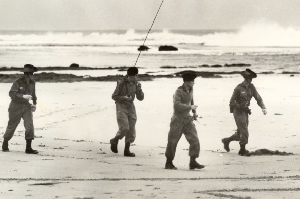An army search party equipped with two-way radio look for Harold Holt on Cheviot Beach.