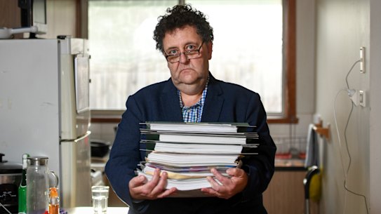 Davidh Digman in his Seaford, Melbourne home, holding his robo-debt files. 