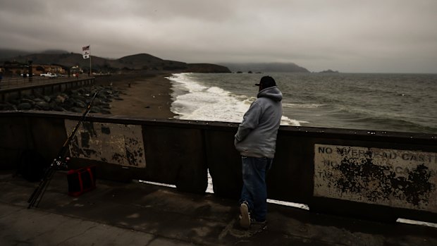 A fisherman looks out at the beach where a tsunami advisory was in effect in Pacifica, California.