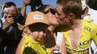 Jonas Vingegaard kisses his wife Trine Hansen, who is holding their child Frida, as they celebrate an almost certain stage of the Tour de France cycling race.