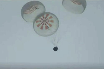 In this image taken from SpaceX video a SpaceX capsule carrying four people parachutes into the Atlantic Ocean off the Florida coast.