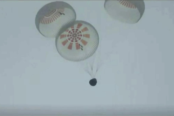 In this image taken from SpaceX video a SpaceX capsule carrying four people parachutes into the Atlantic Ocean off the Florida coast.