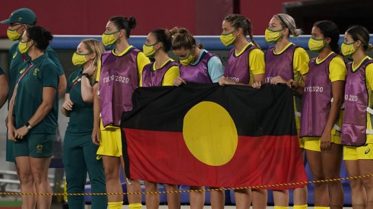 The Matildas line up behind the Aboriginal flag in Tokyo.