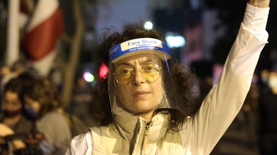 A protester wearing a protective face shield gestures during an anti-government demonstration outside the headquarters of the Lebanese central bank in Beirut, Lebanon. 