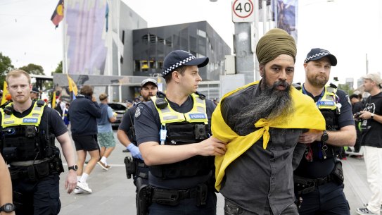 Police officers lead away a protester at Federation Square on Sunday.