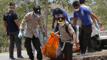 Rescue teams carry the body of a tsunami victim during a mass burial in Palu, Central Sulawesi, Indonesia, on Monday.