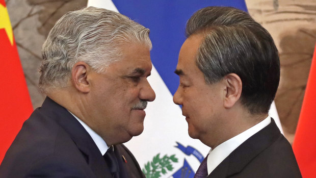 Dominican Foreign Minister Miguel Vargas, left, hugs  Chinese Foreign Minister Wang Yi after they signed the joint communique at the Diaoyutai State Guesthouse in Beijing, on Tuesday.