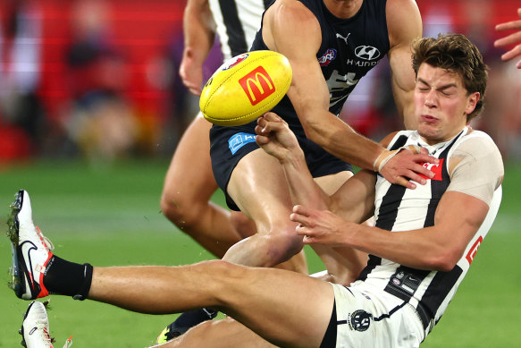 Patrick Lipinski of the Magpies handballs whilst being tackled.