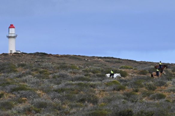 Mounted police scour the hills behind the Blowholes campsite, where Cleo Smith went missing from, on Thursday while soldiers fly a drone from near a lighthouse.