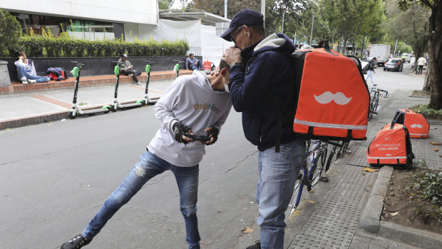 Venezuelan bicycle courier Luis Tarre, 60, kisses the head of his 20-year-old son Raul as they wait for Rappi delivery orders. A large number of food couriers in Bogota, Colombia, have basically become full-time workers, and MPs are considering regulations to boost protection for the workers. 