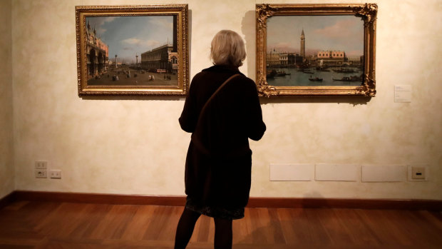 A woman looks at the oil on canvas paintings "The Molo from the Bacino di San Marco" right, and "The Piazza San Marco and Piazzetta looking South", by 18th century Venetian master Giovanni Antonio Canal, known as Canaletto, displayed during the press preview of the exhibition "Canaletto 1697 - 1768", at the Braschi Palace, in Rome.