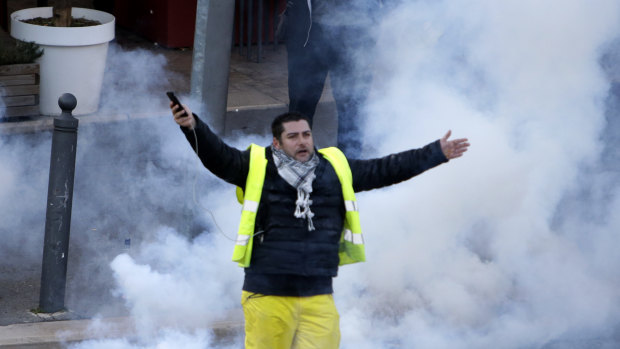 A yellow vest demonstrator gestures through tear gas during a protest on Saturday in Marseille, southern France. 