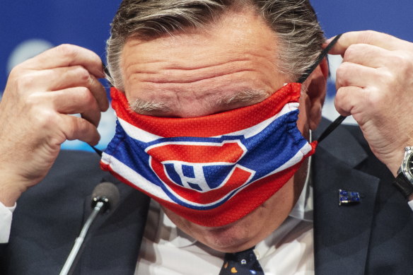 Quebec Premier Francois Legault puts on a Montreal Canadiens face mask as he finishes last Thursday's daily COVID-19 press briefing.