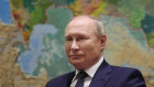 Russian President Vladimir Putin stands before a map of Russia and the region - where his citizens are fleeing.