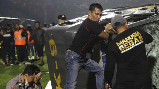 Officers examine a damaged police vehicle following a clash between supporters of two Indonesian soccer teams at Kanjuruhan Stadium in Malang, East Java, Indonesia.