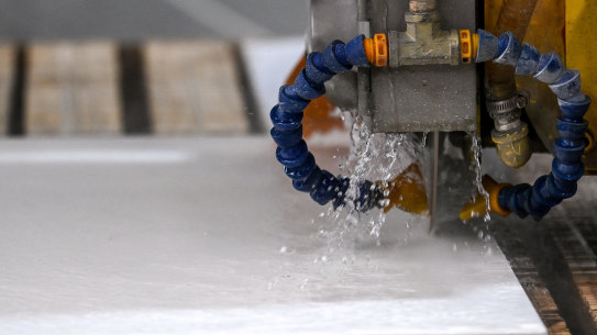 Engineered stone being water cut in a factory.