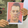 In these image released by Indonesian Police, Bayu Suseno, spokesperson for the Cartenz 2024 Peace Task Force, holds portrait of Glen Malcolm Conning, a pilot for Indonesian aviation company PT Intan Angkasa Air Service, during a press conference in Timika, Indonesia, Monday, Aug. 5, 2024. Gunmen stormed a helicopter and killed the New Zealand pilot shortly after it landed in Indonesia’s restive Papua region on Monday, and they released two health workers and two children it was carrying, police said. (Indonesian Police via AP)