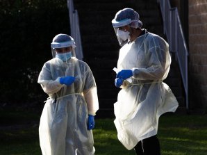 Healthcare workers gown up to perform COVID-19 testing. Testing numbers in NSW have dropped.