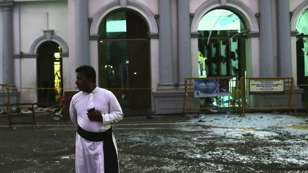 A Sri Lankan catholic priest stands near broken glass in front St. Anthony's Church in Colombo.