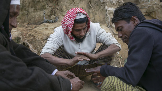 Rohingya refugees warm themselves by a fire in a refugee camp in Cox's Bazar, Bangladesh. 