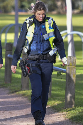 A female police officer holds a white rose to place near where Eurydice Dixon was killed.