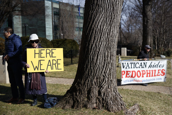 A group with Catholic Laity for Orthodox Bishops and Reform, gathers to pray, left, as John Wojnowski, right, holds a sign outside the Apostolic Nunciature of the Holy See in Washington last year.