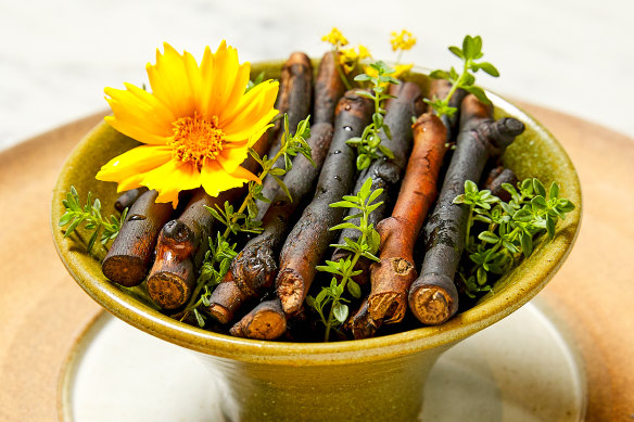 ... sits atop a bowl of crocodile broth covered in charred oak branches.