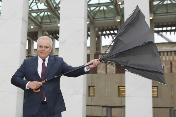 Prime Minister Scott Morrison carrying an umbrella arrives for breakfast television interviews on the front lawn of Parliament House on Wednesday.