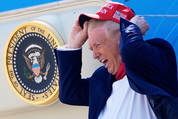 President Donald Trump holds his hat in the wind while disembarking Air Force One last week.