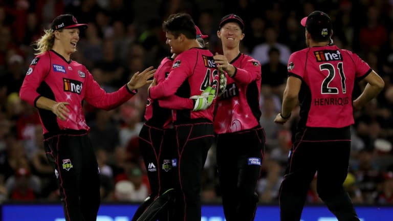 Pretty in pink: Ben Manenti and the Sixers celebrate the wicket of Mackenzie Harvey on the way to victory in Melbourne.